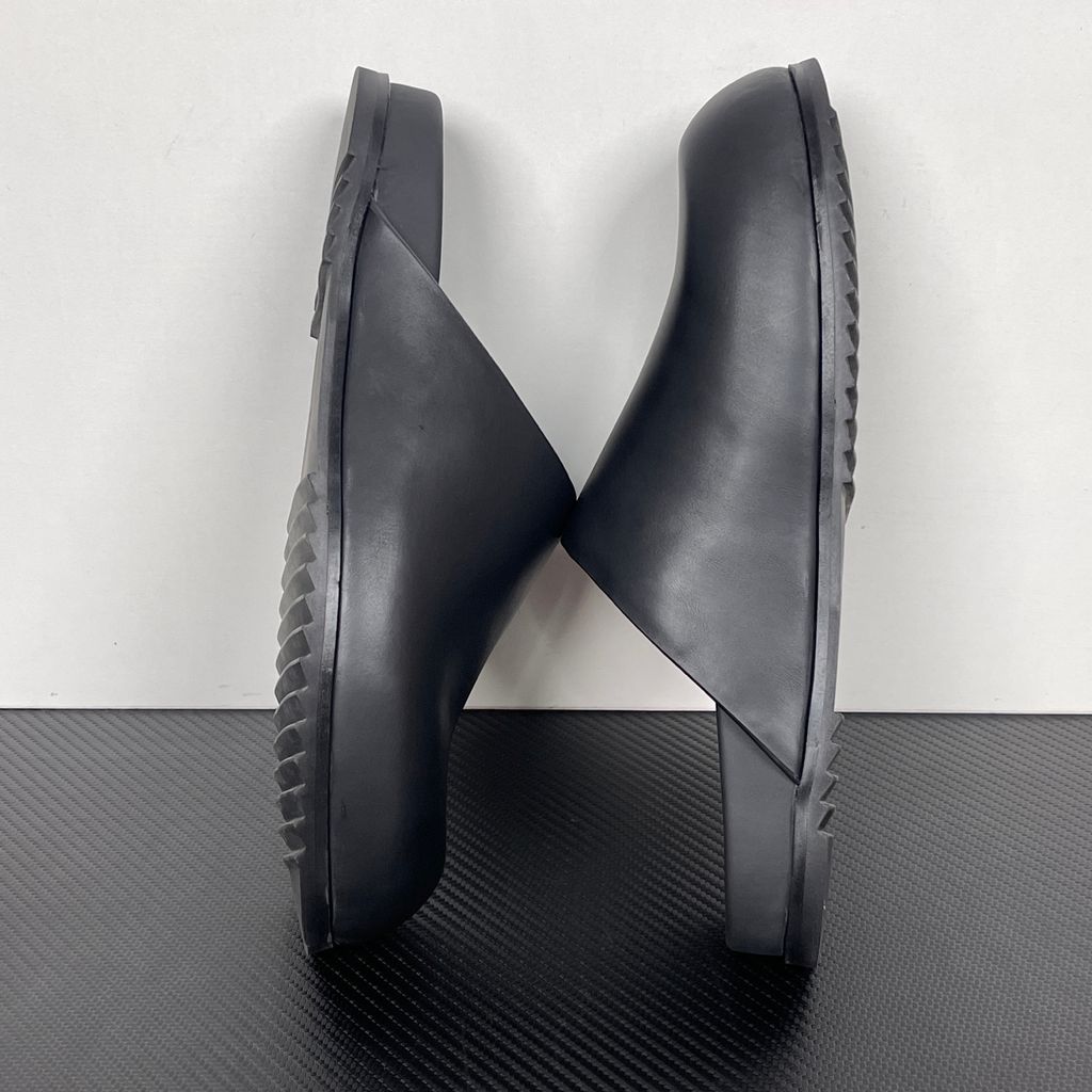 Side profile of the Rick Owens Mule Granola in smooth black leather, featuring a minimalist slip-on silhouette, an exaggerated rounded toe box, and a signature dark jagged rubber outsole.