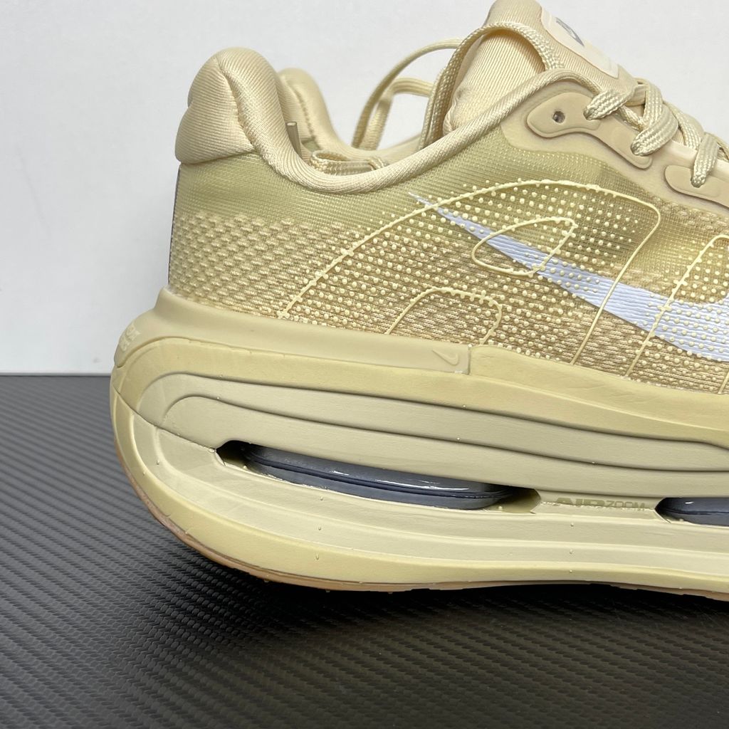 Side profile of the Nike Air Zoom Vomero Premium sneaker in a tonal Desert Khaki and Light Khaki colorway, featuring a complex layered upper of breathable mesh and premium suede overlays, resting on a chunky cushioned midsole.