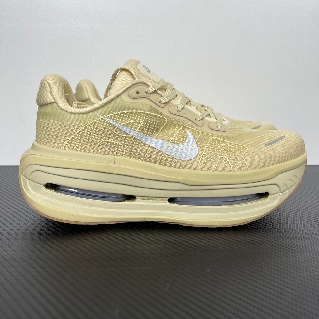 Side profile of the Nike Air Zoom Vomero Premium sneaker in a tonal Desert Khaki and Light Khaki colorway, featuring a complex layered upper of breathable mesh and premium suede overlays, resting on a chunky cushioned midsole.