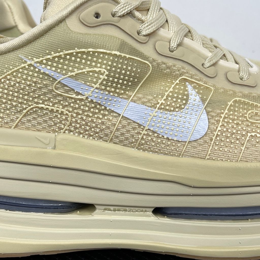 Side profile of the Nike Air Zoom Vomero Premium sneaker in a tonal Desert Khaki and Light Khaki colorway, featuring a complex layered upper of breathable mesh and premium suede overlays, resting on a chunky cushioned midsole.