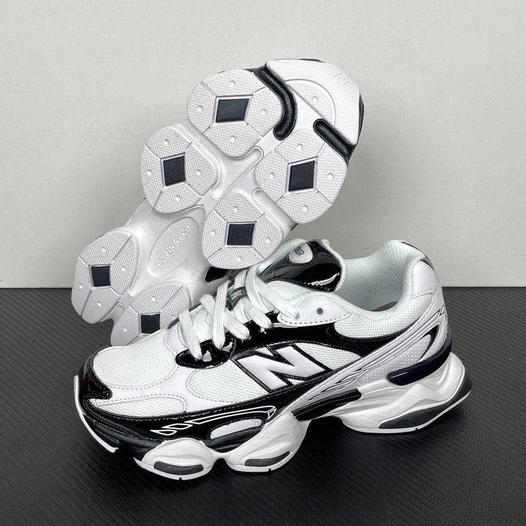 Side profile of the New Balance 9060 sneaker in a sleek black and white colorway, featuring a complex mixed-material upper of suede and mesh, a prominent contrasting 'N' logo, and a highly sculpted chunky midsole with distinctive pod detailing.
