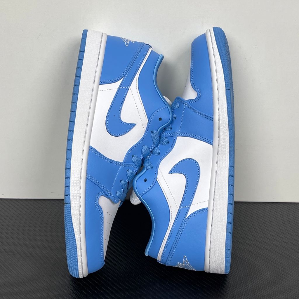 Side profile of the Air Jordan 1 Low sneaker in a classic 'UNC' colorway, featuring a crisp white leather base with vibrant University Blue overlays, a matching Swoosh, and a white midsole resting on a blue rubber outsole.