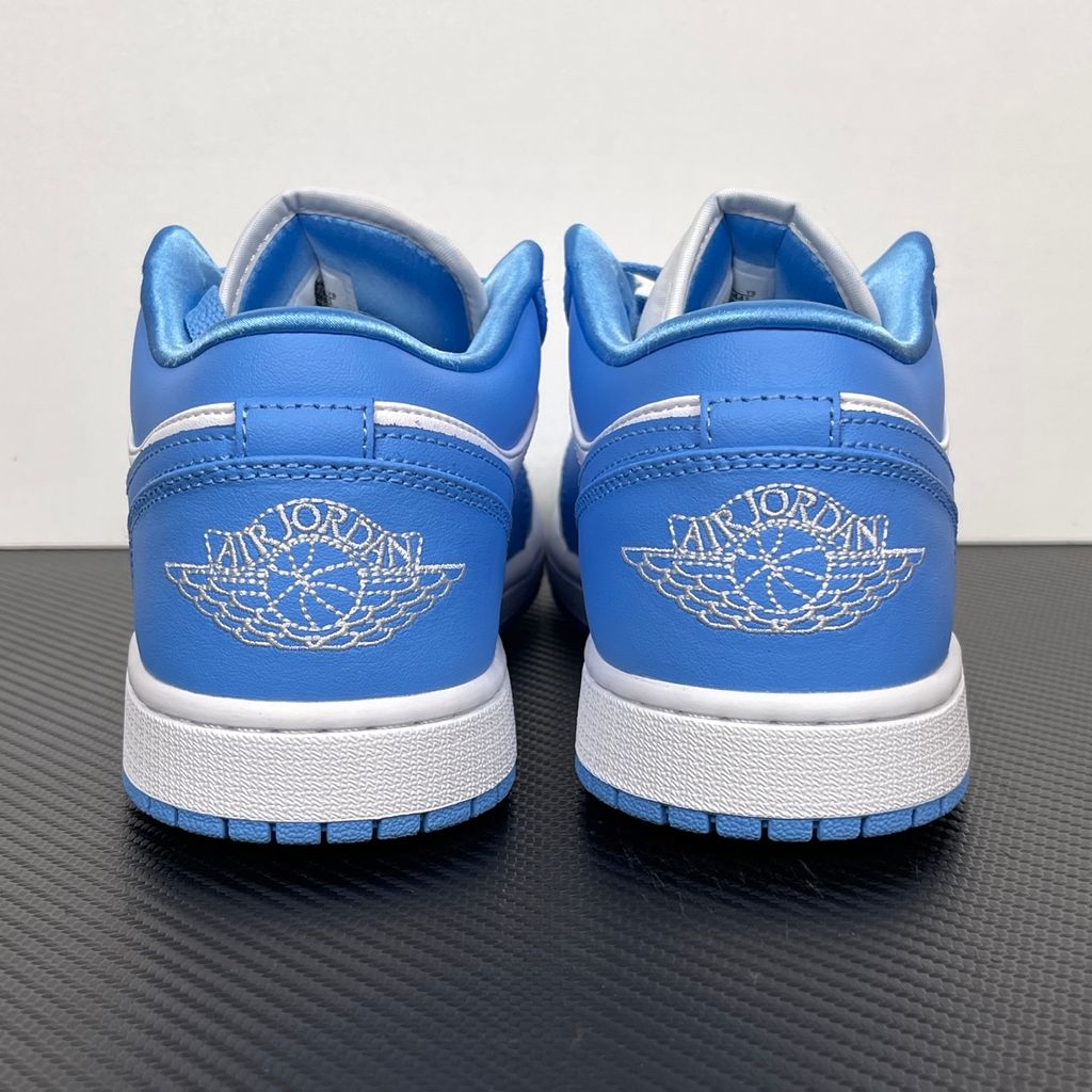 Side profile of the Air Jordan 1 Low sneaker in a classic 'UNC' colorway, featuring a crisp white leather base with vibrant University Blue overlays, a matching Swoosh, and a white midsole resting on a blue rubber outsole.