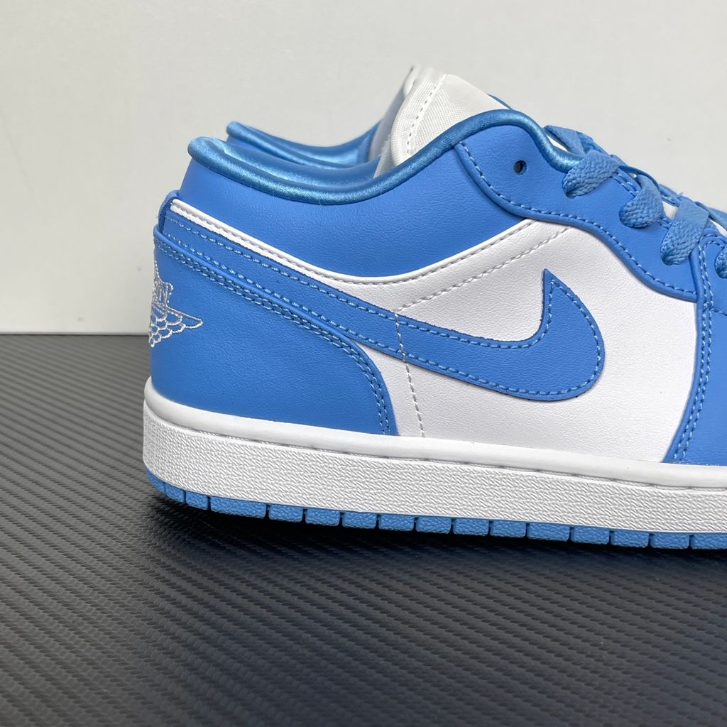 Side profile of the Air Jordan 1 Low sneaker in a classic 'UNC' colorway, featuring a crisp white leather base with vibrant University Blue overlays, a matching Swoosh, and a white midsole resting on a blue rubber outsole.