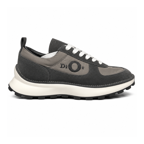 Side profile of the Dior Squash sneaker in a black and grey colorway, featuring a mix of premium calf suede and technical nylon, distinctive 'Dior' side embroidery with an oversized 'O', and a chunky white midsole with a lugged black outsole.
