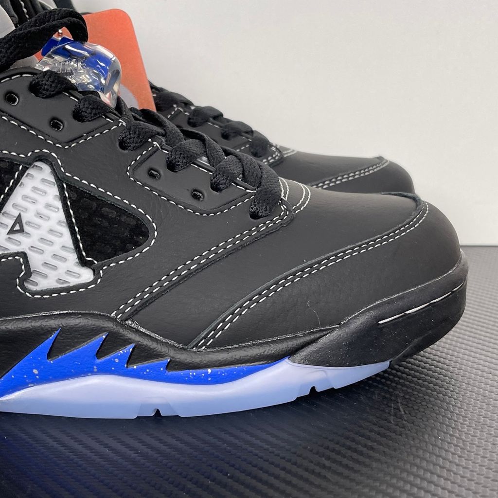 Side profile of the Jordan 5 Retro x Awake NY sneaker in a stealthy black colorway, featuring a premium textured upper, classic translucent midfoot netting, reflective tongue detailing, and signature co-branding on the heel.