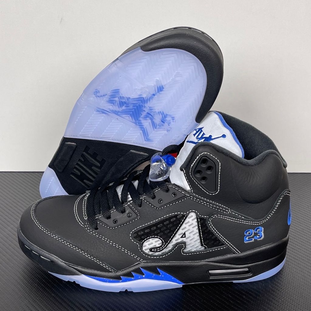 Side profile of the Jordan 5 Retro x Awake NY sneaker in a stealthy black colorway, featuring a premium textured upper, classic translucent midfoot netting, reflective tongue detailing, and signature co-branding on the heel.