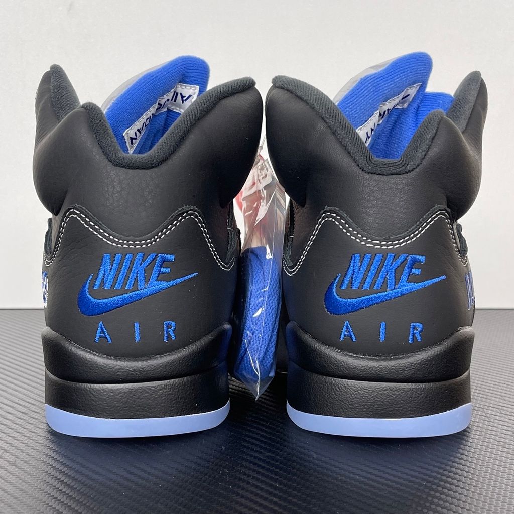 Side profile of the Jordan 5 Retro x Awake NY sneaker in a stealthy black colorway, featuring a premium textured upper, classic translucent midfoot netting, reflective tongue detailing, and signature co-branding on the heel.