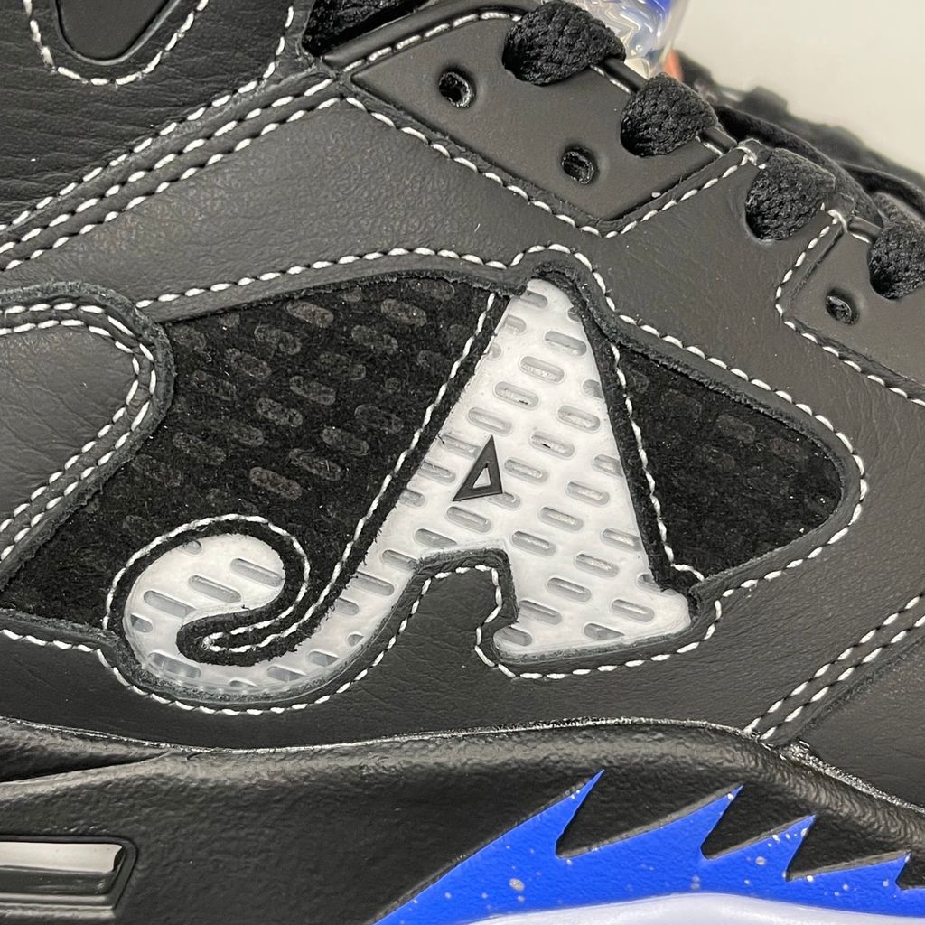 Side profile of the Jordan 5 Retro x Awake NY sneaker in a stealthy black colorway, featuring a premium textured upper, classic translucent midfoot netting, reflective tongue detailing, and signature co-branding on the heel.