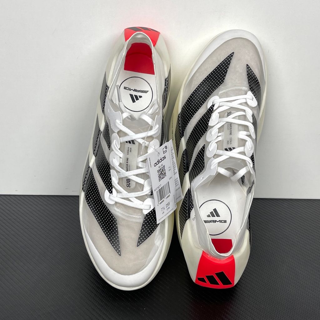 Side profile of the adidas Adizero Prime X EVO running shoe featuring a breathable Cloud White upper, striking Core Black Three Stripes branding, vibrant Lucid Red accents, and a massive, hyper-stacked Lightstrike Pro foam midsole.