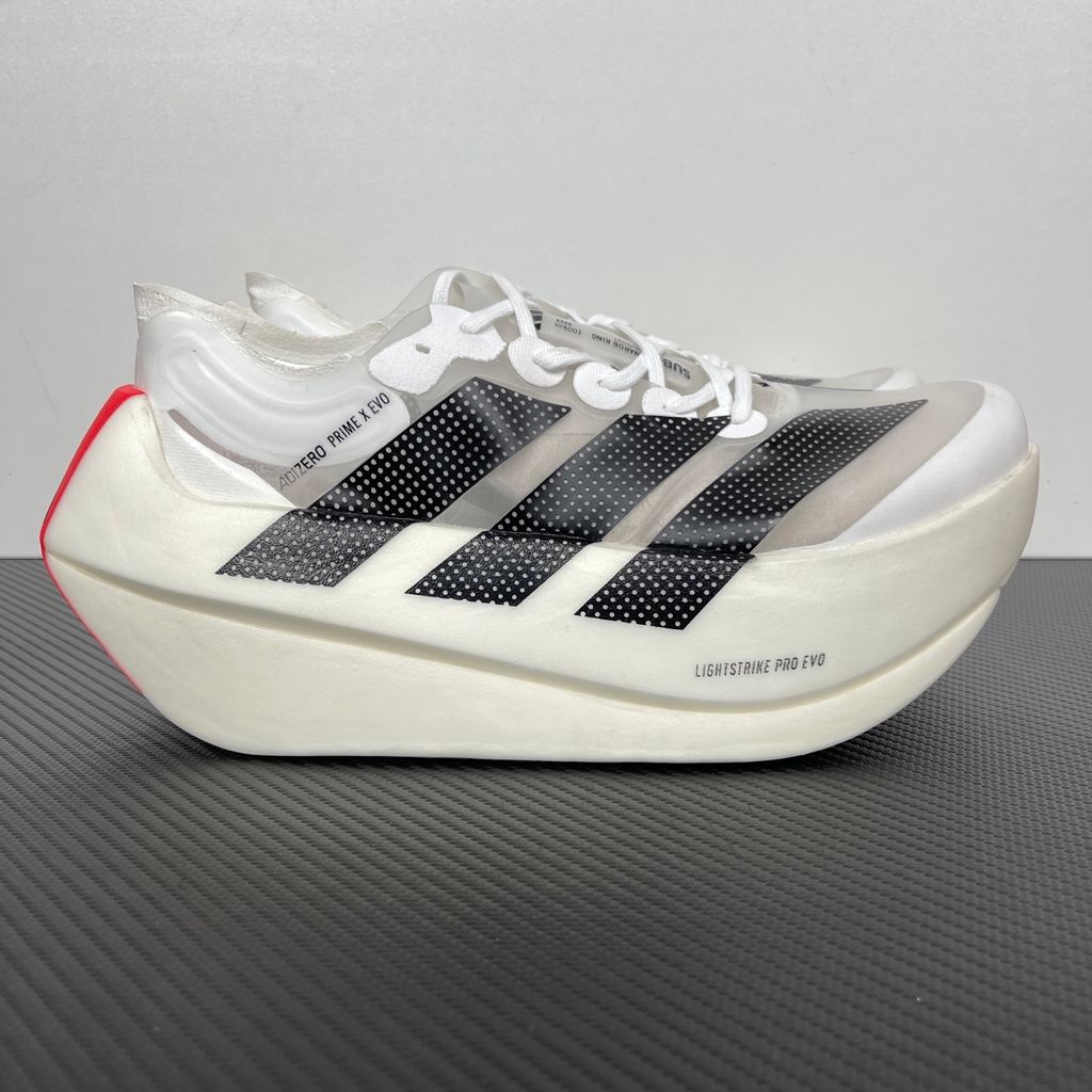 Side profile of the adidas Adizero Prime X EVO running shoe featuring a breathable Cloud White upper, striking Core Black Three Stripes branding, vibrant Lucid Red accents, and a massive, hyper-stacked Lightstrike Pro foam midsole.