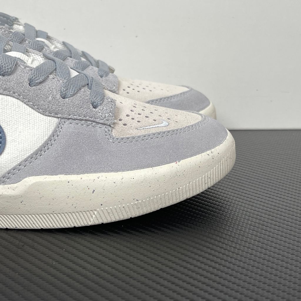 Side profile of the Nike SB Force 58 skate shoe featuring a creamy Coconut Milk canvas and suede upper, accented by a Neutral Olive green Swoosh and detailing, resting on a crisp white sole with a flexible tri-star tread.