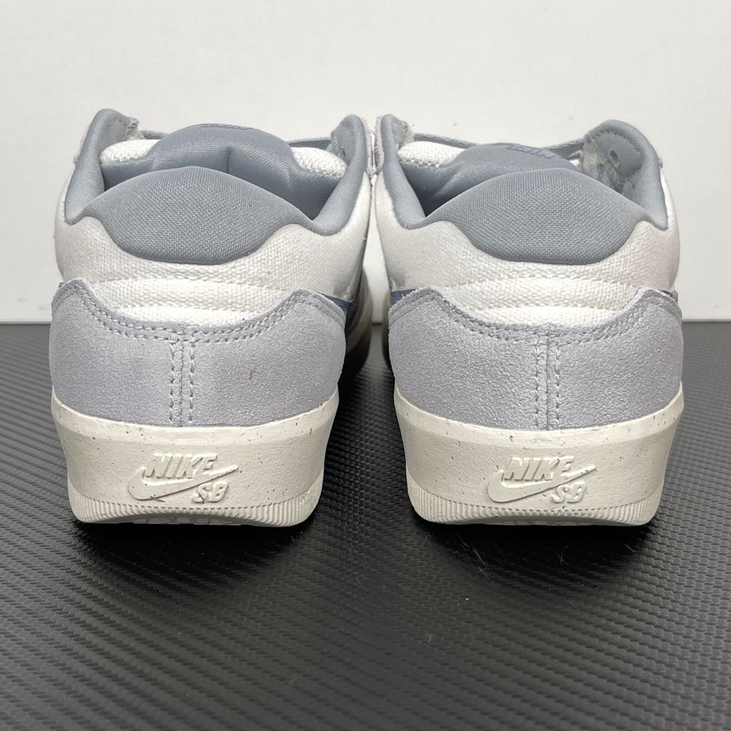 Side profile of the Nike SB Force 58 skate shoe featuring a creamy Coconut Milk canvas and suede upper, accented by a Neutral Olive green Swoosh and detailing, resting on a crisp white sole with a flexible tri-star tread.