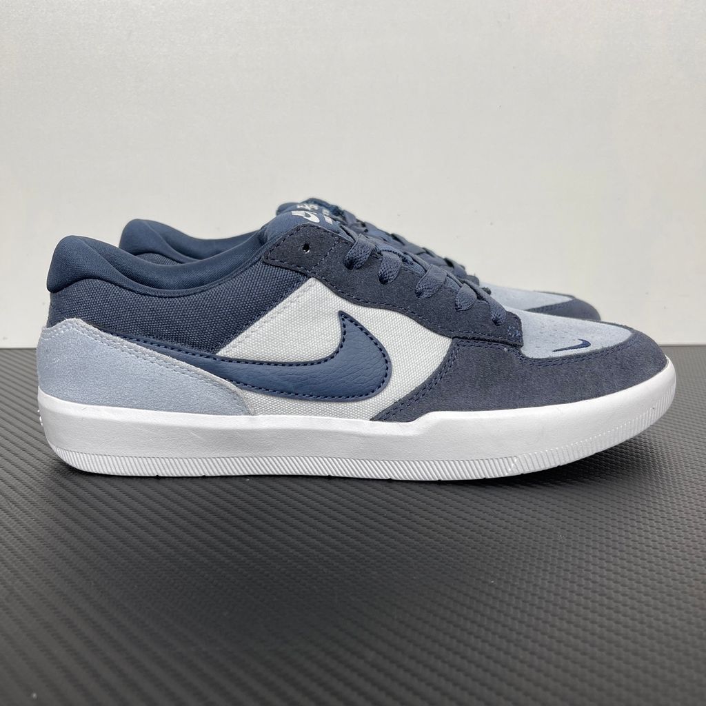 Side profile of the Nike SB Force 58 skate shoe featuring a soft Light Armory Blue canvas and suede upper, accented by a deep Thunder Blue Swoosh and detailing, resting on a crisp white sole with a flexible tri-star tread.