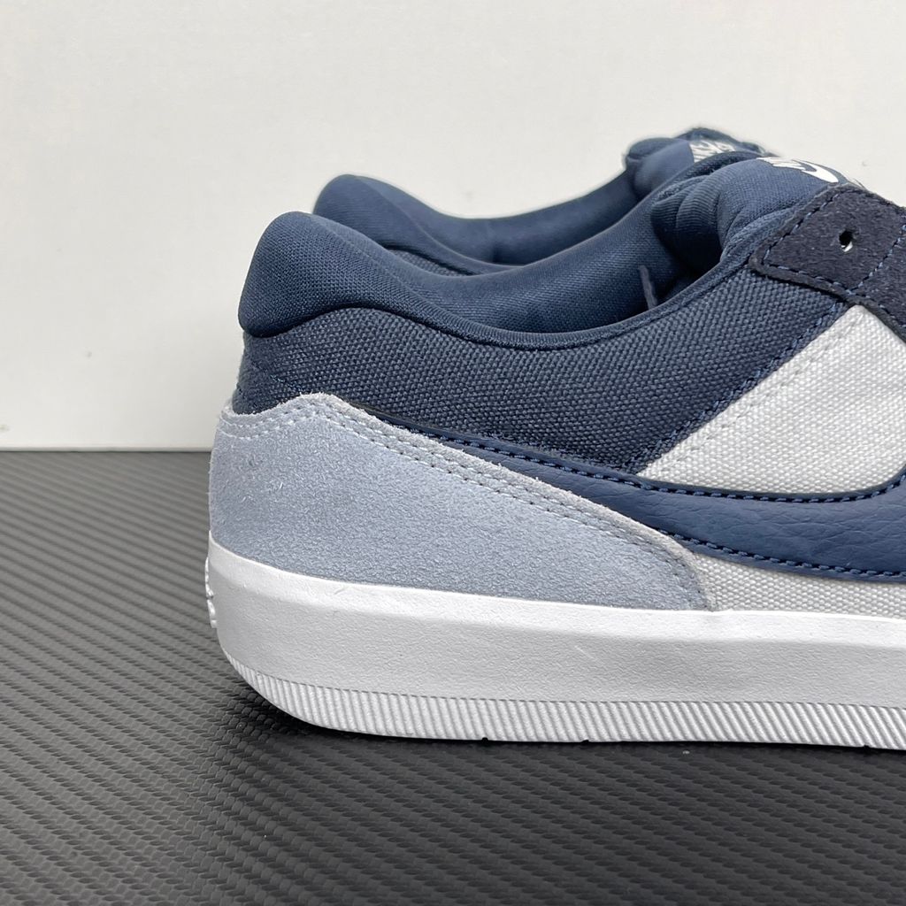 Side profile of the Nike SB Force 58 skate shoe featuring a soft Light Armory Blue canvas and suede upper, accented by a deep Thunder Blue Swoosh and detailing, resting on a crisp white sole with a flexible tri-star tread.