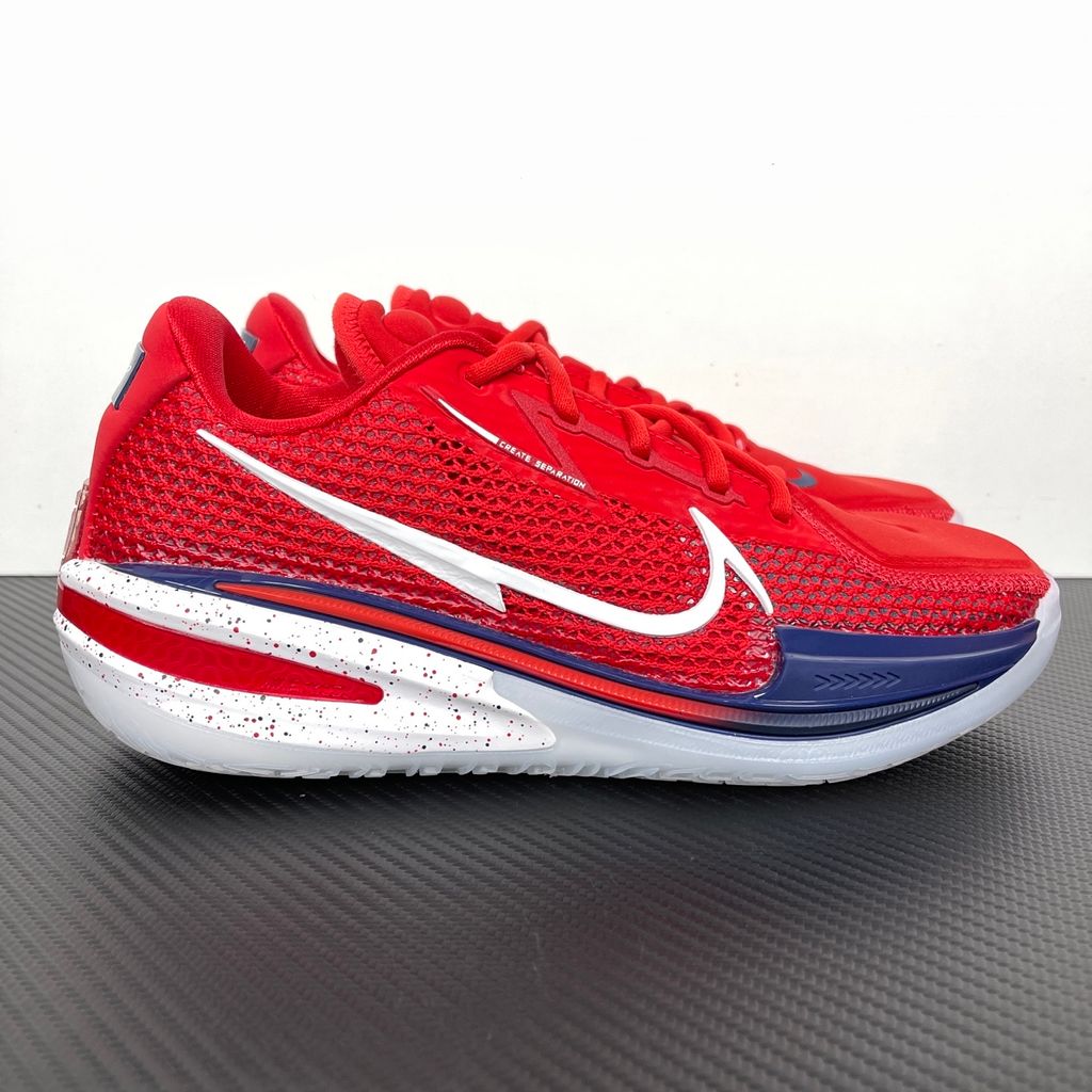Side profile of the Nike Air Zoom G.T. Cut basketball shoe in the Team USA colorway, featuring a vibrant Sport Red engineered mesh upper, contrasted by navy blue detailing, a crisp white Swoosh, and a highly sculpted responsive sole unit.