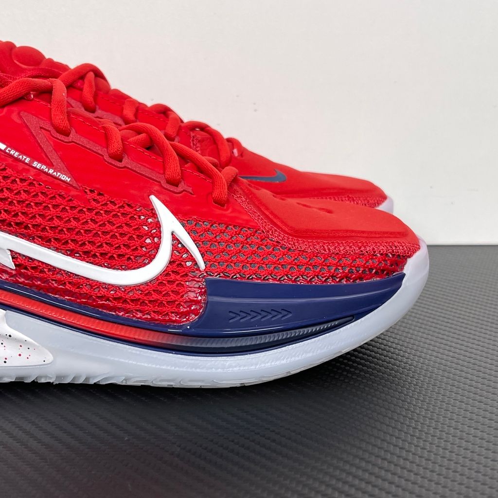 Side profile of the Nike Air Zoom G.T. Cut basketball shoe in the Team USA colorway, featuring a vibrant Sport Red engineered mesh upper, contrasted by navy blue detailing, a crisp white Swoosh, and a highly sculpted responsive sole unit.