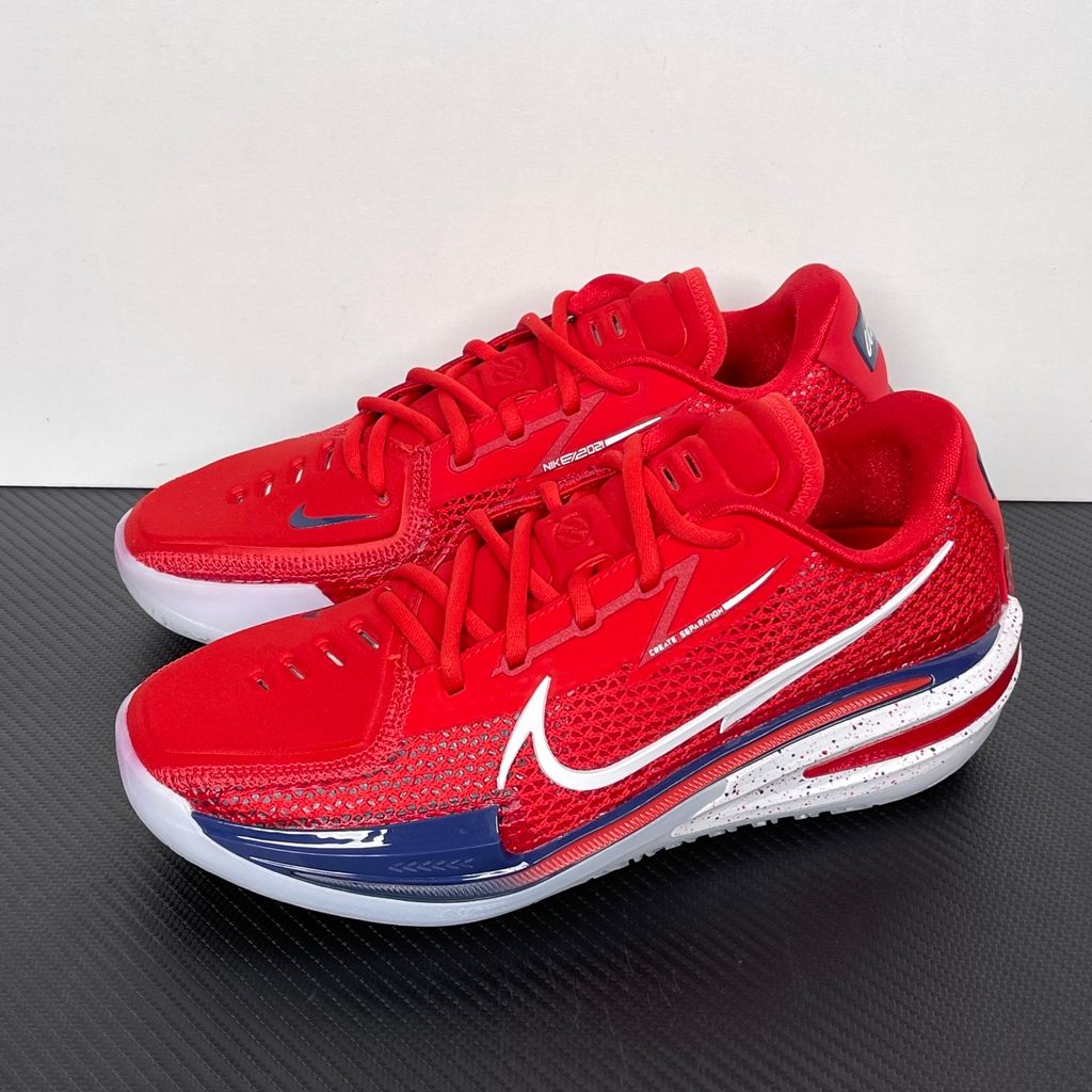 Side profile of the Nike Air Zoom G.T. Cut basketball shoe in the Team USA colorway, featuring a vibrant Sport Red engineered mesh upper, contrasted by navy blue detailing, a crisp white Swoosh, and a highly sculpted responsive sole unit.