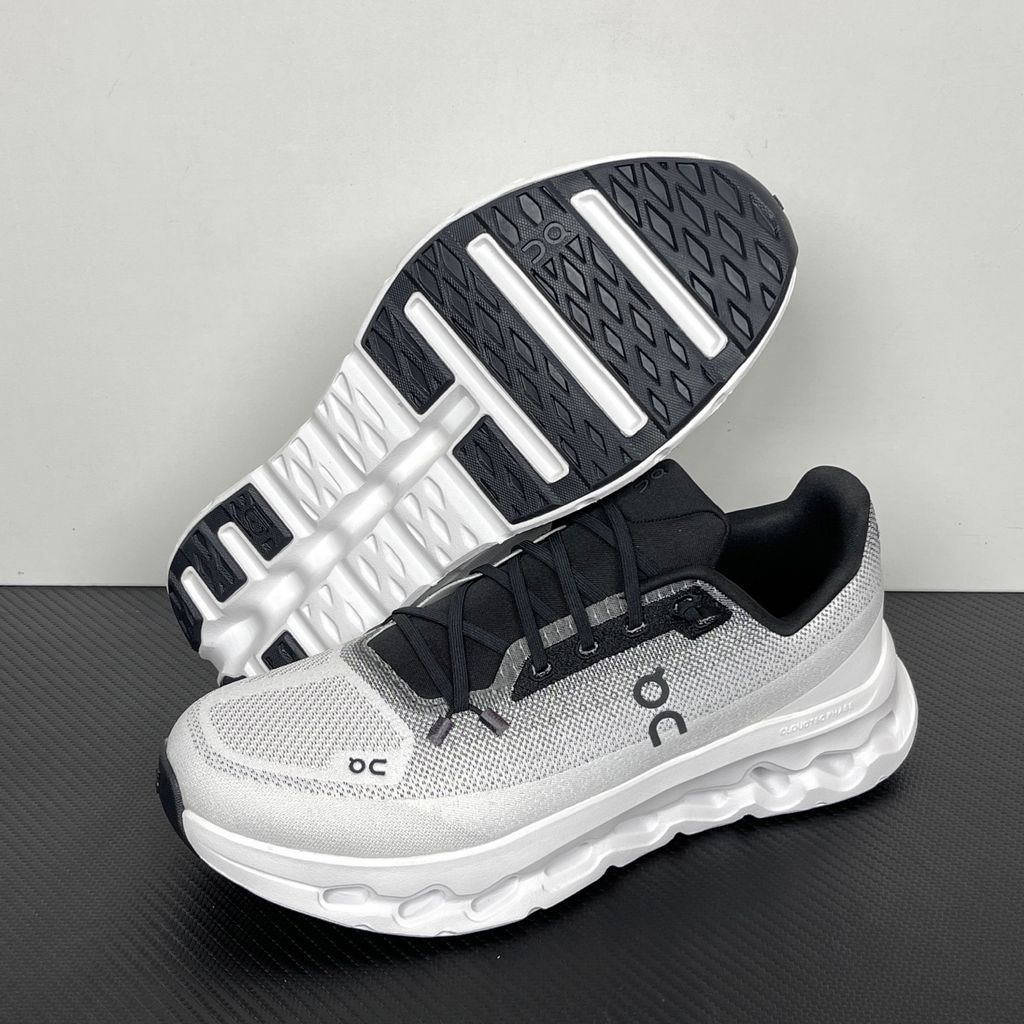 Side profile of the On Running Cloudtilt sneaker featuring a sleek, lightweight black knit upper with a sock-like collar, integrated speed lacing, and a contrasting ivory midsole showcasing the collapsing CloudTec Phase® pods.