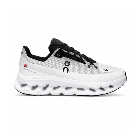 Side profile of the On Running Cloudtilt sneaker featuring a sleek, lightweight black knit upper with a sock-like collar, integrated speed lacing, and a contrasting ivory midsole showcasing the collapsing CloudTec Phase® pods.