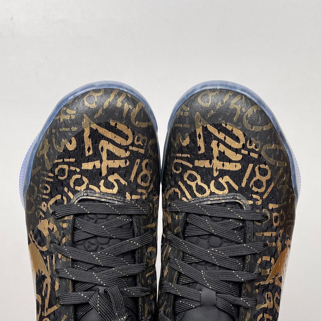 Side profile of the Nike Kobe 11 Protro basketball shoe in the Mamba Day colorway, featuring a sleek black upper with striking metallic gold Swoosh detailing, signature Kobe branding, and a translucent rubber outsole.