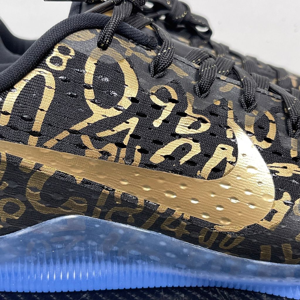 Side profile of the Nike Kobe 11 Protro basketball shoe in the Mamba Day colorway, featuring a sleek black upper with striking metallic gold Swoosh detailing, signature Kobe branding, and a translucent rubber outsole.