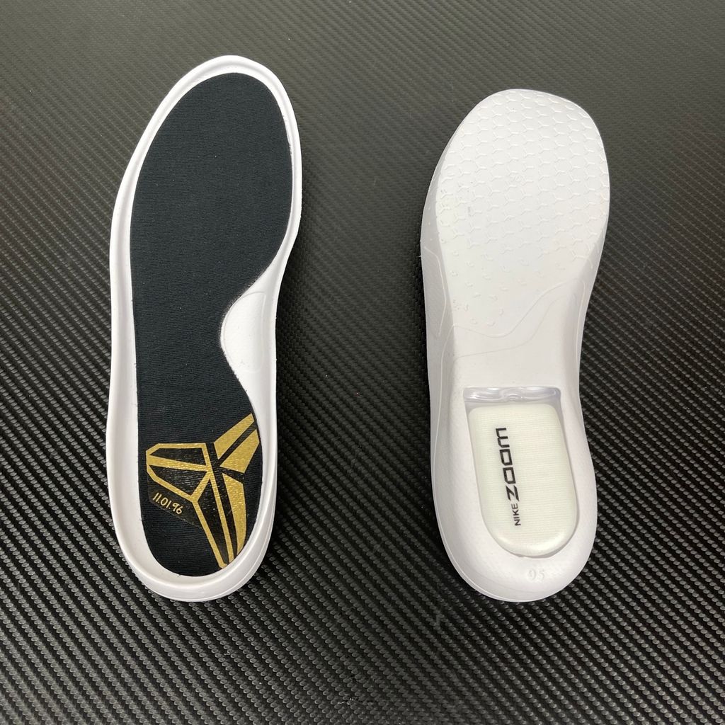 Side profile of the Nike Kobe 11 Protro basketball shoe in the Mamba Day colorway, featuring a sleek black upper with striking metallic gold Swoosh detailing, signature Kobe branding, and a translucent rubber outsole.