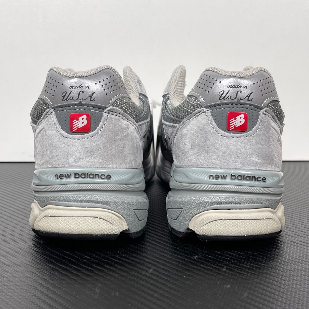Side profile of the classic New Balance 990v3 Made in USA sneaker featuring a premium grey pigskin suede and mesh upper, silver reflective 'N' logo, and a split white and grey ENCAP midsole.