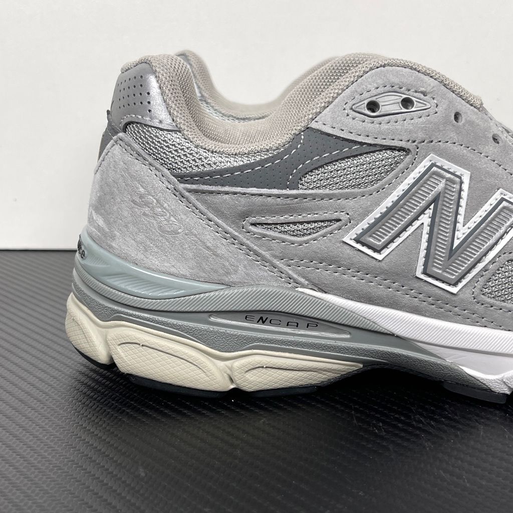 Side profile of the classic New Balance 990v3 Made in USA sneaker featuring a premium grey pigskin suede and mesh upper, silver reflective 'N' logo, and a split white and grey ENCAP midsole.