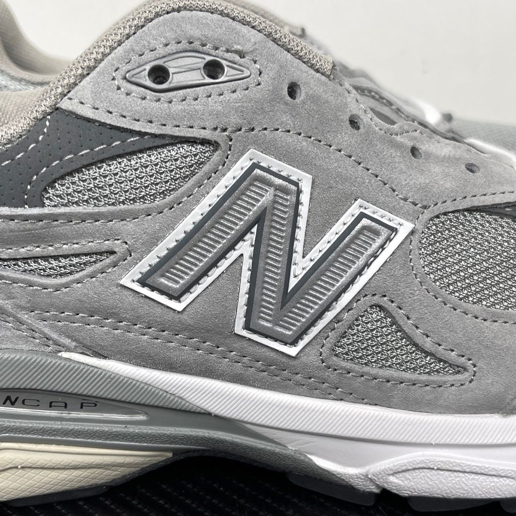 Side profile of the classic New Balance 990v3 Made in USA sneaker featuring a premium grey pigskin suede and mesh upper, silver reflective 'N' logo, and a split white and grey ENCAP midsole.