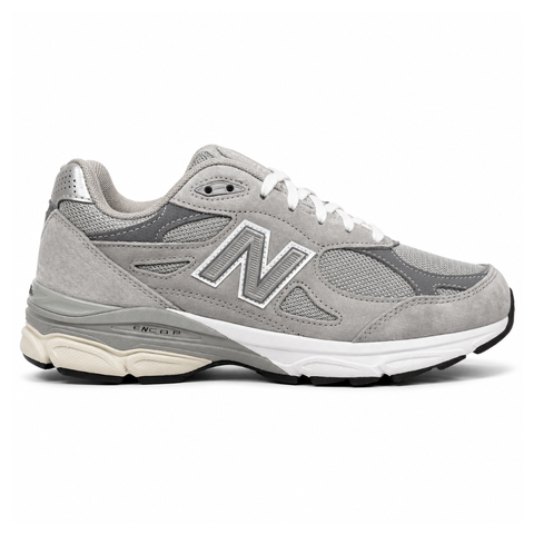 Side profile of the classic New Balance 990v3 Made in USA sneaker featuring a premium grey pigskin suede and mesh upper, silver reflective 'N' logo, and a split white and grey ENCAP midsole.