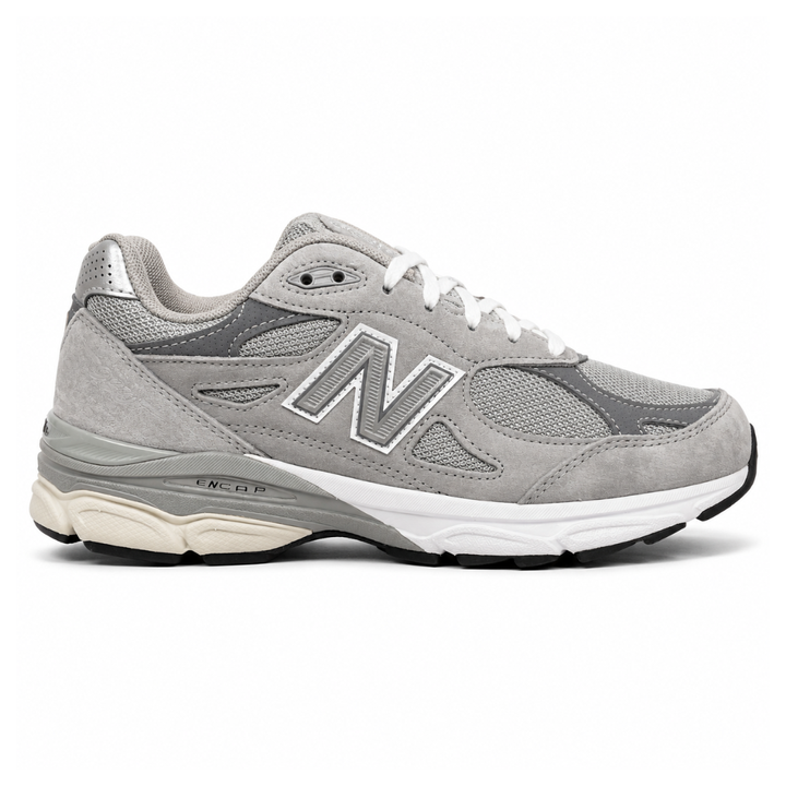 Side profile of the classic New Balance 990v3 Made in USA sneaker featuring a premium grey pigskin suede and mesh upper, silver reflective 'N' logo, and a split white and grey ENCAP midsole.