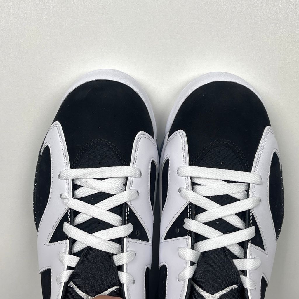 Side profile of the Air Jordan 6 Retro 'Oreo' (2026) sneaker featuring a crisp white leather upper, contrasting black nubuck underlays, signature speckled midsole detailing, an iconic lace toggle, and an icy translucent rubber outsole.