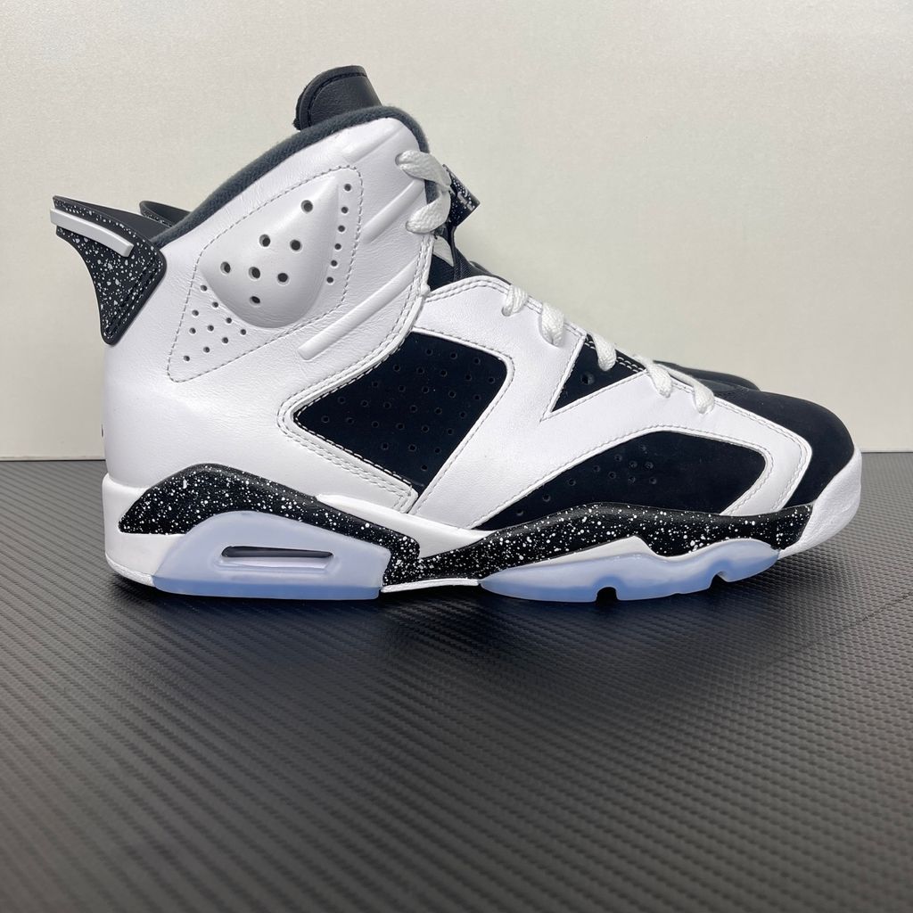 Side profile of the Air Jordan 6 Retro 'Oreo' (2026) sneaker featuring a crisp white leather upper, contrasting black nubuck underlays, signature speckled midsole detailing, an iconic lace toggle, and an icy translucent rubber outsole.