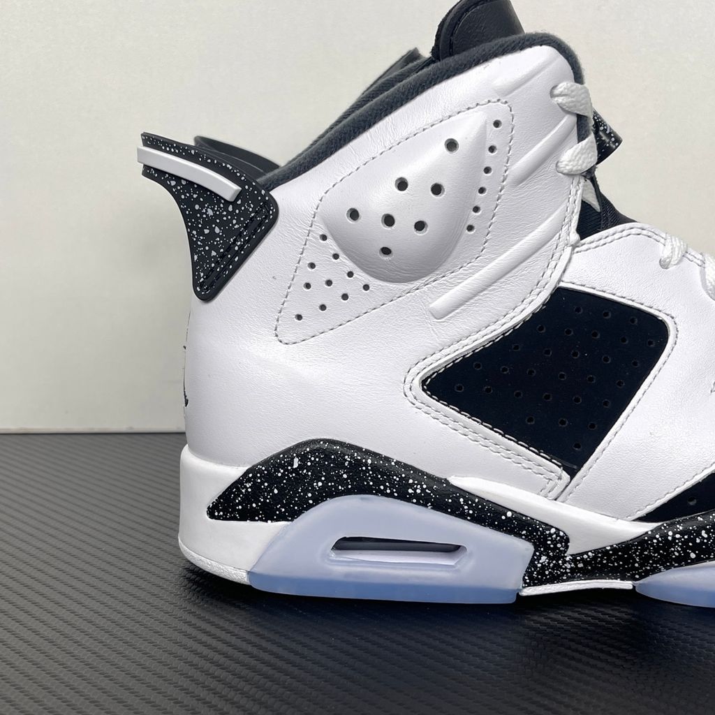 Side profile of the Air Jordan 6 Retro 'Oreo' (2026) sneaker featuring a crisp white leather upper, contrasting black nubuck underlays, signature speckled midsole detailing, an iconic lace toggle, and an icy translucent rubber outsole.