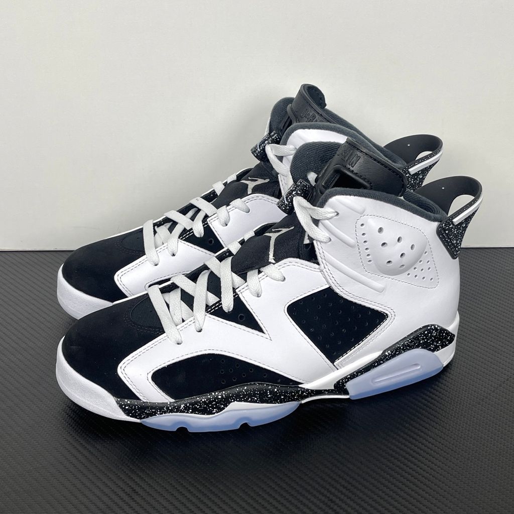Side profile of the Air Jordan 6 Retro 'Oreo' (2026) sneaker featuring a crisp white leather upper, contrasting black nubuck underlays, signature speckled midsole detailing, an iconic lace toggle, and an icy translucent rubber outsole.