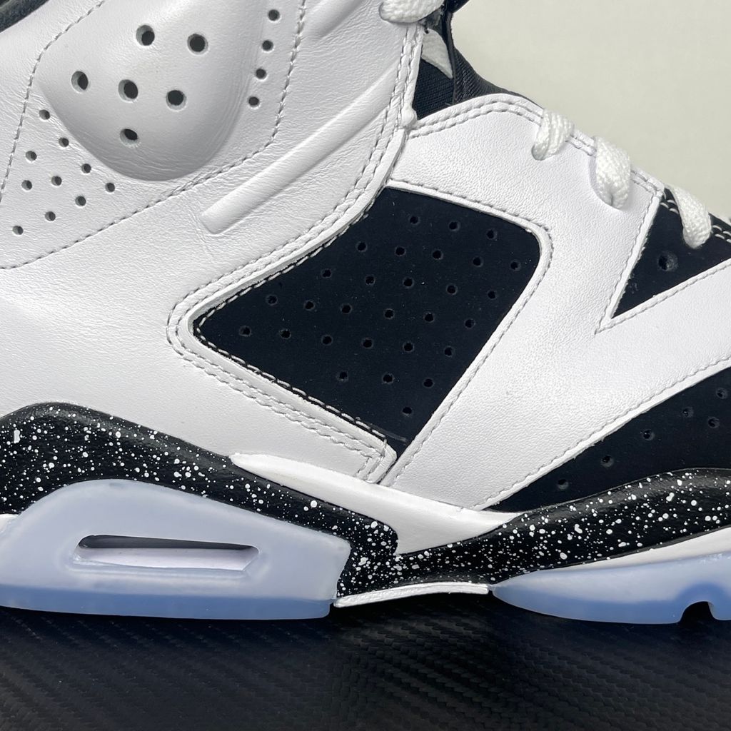 Side profile of the Air Jordan 6 Retro 'Oreo' (2026) sneaker featuring a crisp white leather upper, contrasting black nubuck underlays, signature speckled midsole detailing, an iconic lace toggle, and an icy translucent rubber outsole.