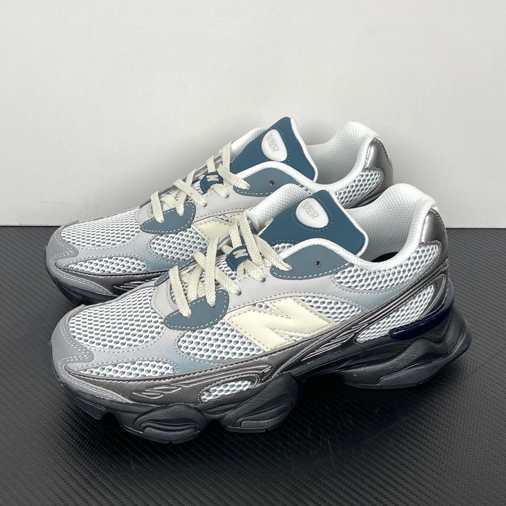Side profile of the New Balance 9060 sneaker featuring a white open-mesh upper, striking metallic silver overlays, a cream 'N' logo, and a dramatic, chunky black wavy midsole with ABZORB cushioning.