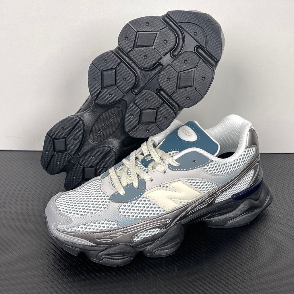 Side profile of the New Balance 9060 sneaker featuring a white open-mesh upper, striking metallic silver overlays, a cream 'N' logo, and a dramatic, chunky black wavy midsole with ABZORB cushioning.