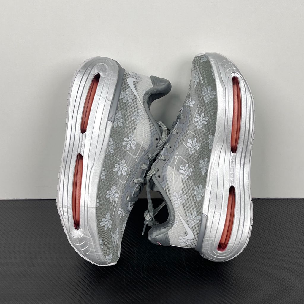 Side profile of the Nike Vomero Premium QS sneaker in a refined Fleur De-Lis and Geyser Grey colorway, featuring a layered mesh and premium synthetic upper, signature plastic side cage, and a responsive Zoom Air midsole.