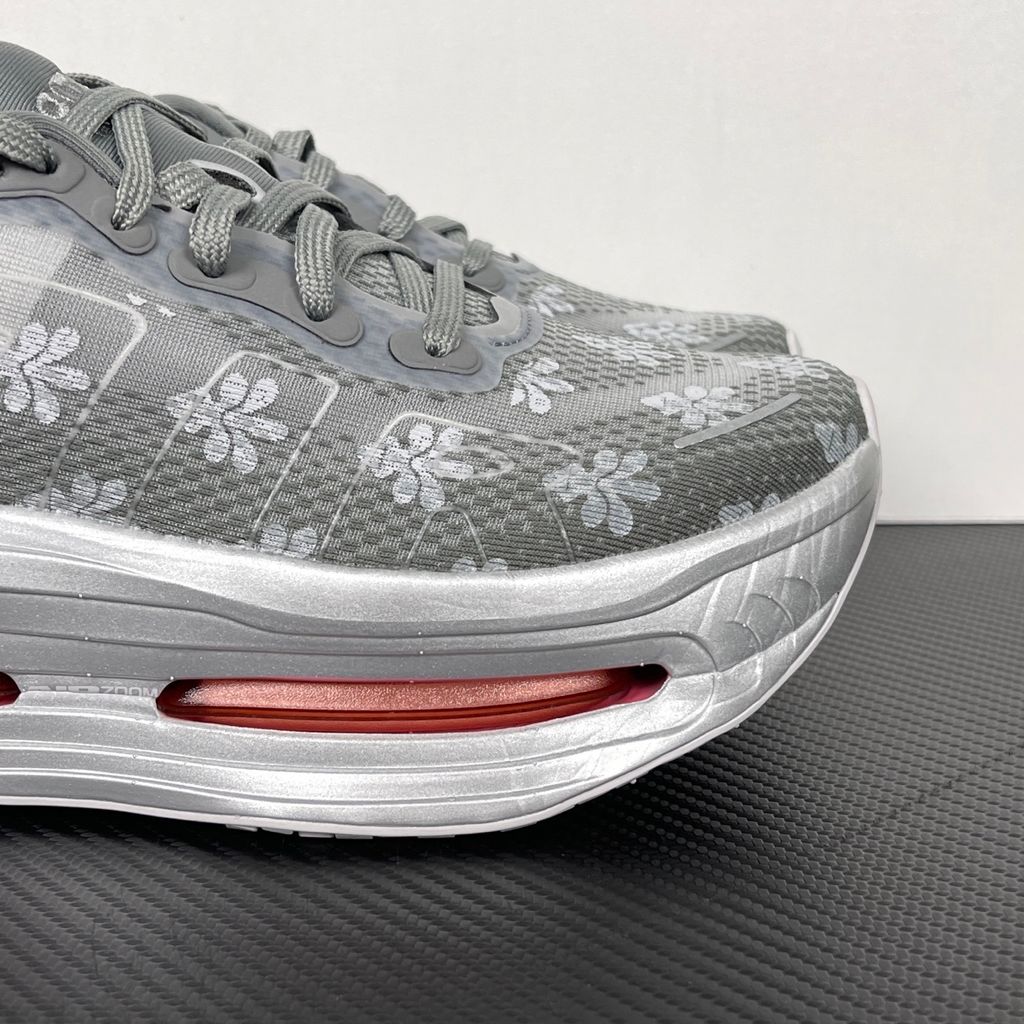 Side profile of the Nike Vomero Premium QS sneaker in a refined Fleur De-Lis and Geyser Grey colorway, featuring a layered mesh and premium synthetic upper, signature plastic side cage, and a responsive Zoom Air midsole.