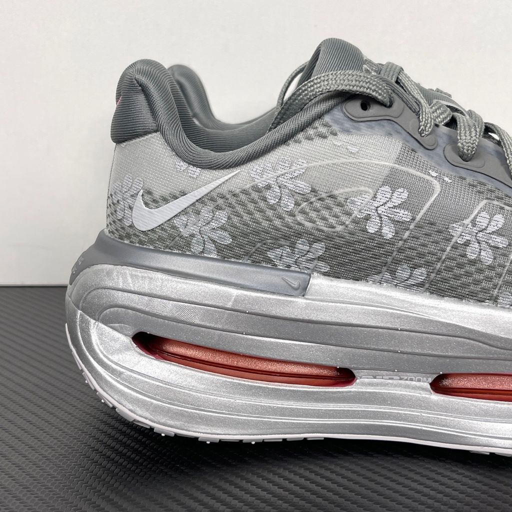 Side profile of the Nike Vomero Premium QS sneaker in a refined Fleur De-Lis and Geyser Grey colorway, featuring a layered mesh and premium synthetic upper, signature plastic side cage, and a responsive Zoom Air midsole.