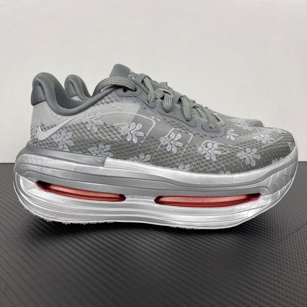 Side profile of the Nike Vomero Premium QS sneaker in a refined Fleur De-Lis and Geyser Grey colorway, featuring a layered mesh and premium synthetic upper, signature plastic side cage, and a responsive Zoom Air midsole.