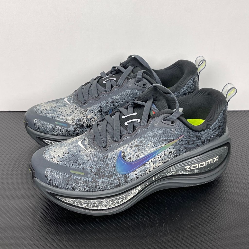 Side profile of the Nike Vomero Plus sneaker in a dark Anthracite and Black colorway with subtle Oatmeal accents, featuring a layered mesh and synthetic upper, a structured midfoot cage, and a responsive Zoom Air midsole.