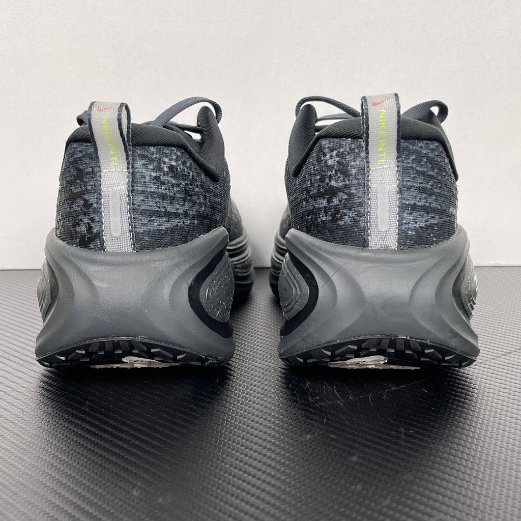Side profile of the Nike Vomero Plus sneaker in a dark Anthracite and Black colorway with subtle Oatmeal accents, featuring a layered mesh and synthetic upper, a structured midfoot cage, and a responsive Zoom Air midsole.