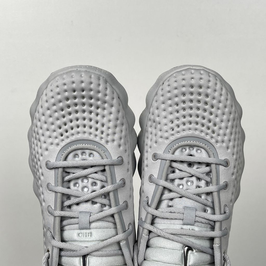 vSide profile of the Nike Vomero Plus sneaker in a dark Anthracite and Black colorway with subtle Oatmeal accents, featuring a layered mesh and synthetic upper, a structured midfoot cage, and a responsive Zoom Air midsole.