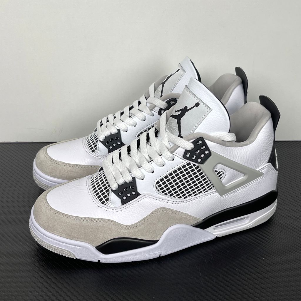 Side profile of the Air Jordan 4 Retro 'Military Black' sneaker featuring a crisp white tumbled leather upper, a light grey suede toe wrap, contrasting black TPU support wings and heel tab, and a white midsole with a visible Air unit.