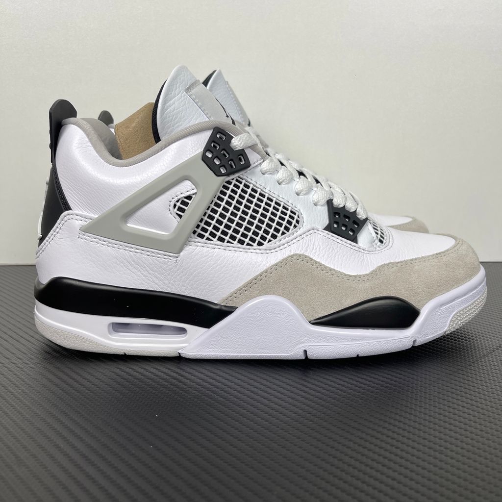 Side profile of the Air Jordan 4 Retro 'Military Black' sneaker featuring a crisp white tumbled leather upper, a light grey suede toe wrap, contrasting black TPU support wings and heel tab, and a white midsole with a visible Air unit.