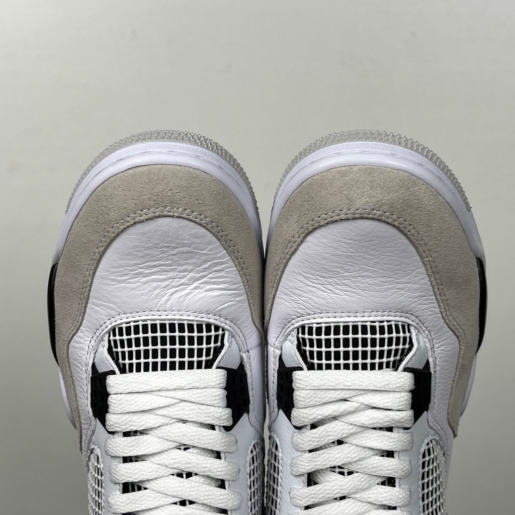 Side profile of the Air Jordan 4 Retro 'Military Black' sneaker featuring a crisp white tumbled leather upper, a light grey suede toe wrap, contrasting black TPU support wings and heel tab, and a white midsole with a visible Air unit.