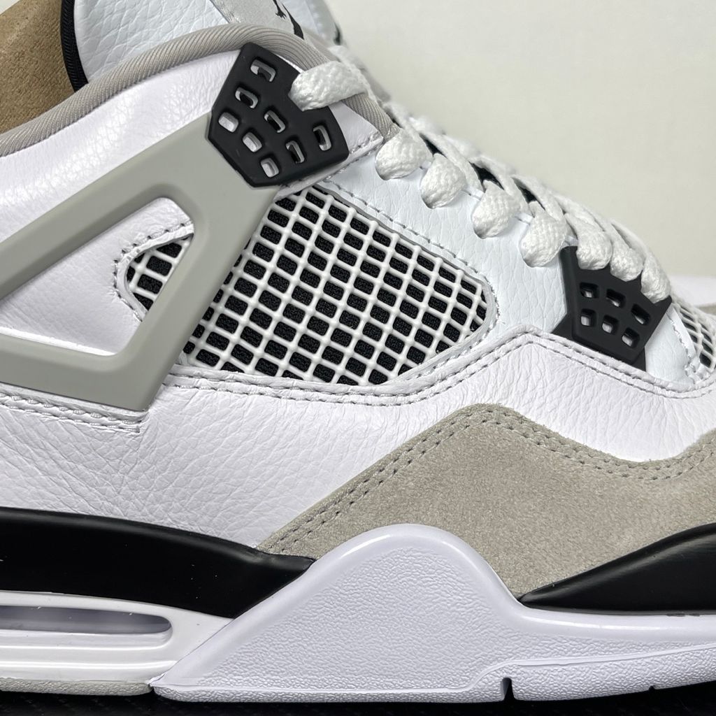 Side profile of the Air Jordan 4 Retro 'Military Black' sneaker featuring a crisp white tumbled leather upper, a light grey suede toe wrap, contrasting black TPU support wings and heel tab, and a white midsole with a visible Air unit.